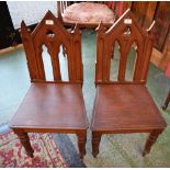 A pair of Gothic Revival oak hall chairs, architectural pierced and carved backs, boarded seat,