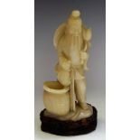 A Chinese soapstone carving, of a fisherman, he stands holding his catch, carved hardwood stand, 24.