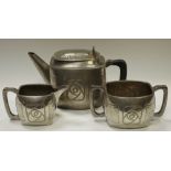 An Arts and Crafts Roundhouse pewter three piece, sinuous chased motif, hammered borders c.