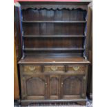 A 20th century oak dresser, outswept cornice above a shaped apron and three plate racks,