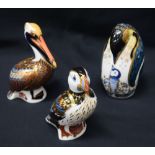 A Royal Crown Derby paperweight, Brown Pelican, gold stopper, boxed; others, Penguin and Chick,