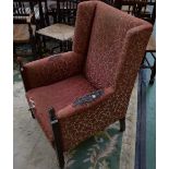 An early 20th century mahogany wingback armchair, stuffed over upholstery,