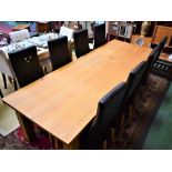 A contemporary light oak dining table, slightly rounded rectangular top, substantial square legs,