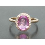 A pink sapphire and diamond cluster ring, central oval pink sapphire approx 1.