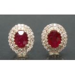 A pair of ruby and diamond cluster earrings, each with a central oval red ruby, approx 1.