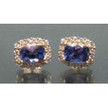 A pair of tanzanite and diamond earrings, each with a central oval violet blue tanzanite, approx 1.