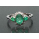 An emerald and diamond cluster ring, central oval emerald approx 0.