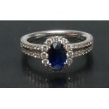 A contemporary sapphire and diamond cluster ring, central oval deep blue sapphire approx 1.