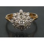 A stepped four layer floral diamond cluster ring, central round brilliant cut diamond approx 0.