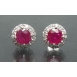 A pair of ruby and diamond earrings, each with a central round cut pinky red ruby approx 1.