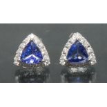 A pair of tanzanite and diamond earrings, each with a central trilliant cut purplish blue tanzanite,