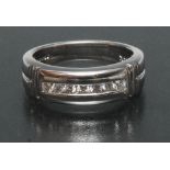 A contemporary design diamond ring, channel set with seven round brilliant cut diamonds,