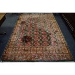 A woollen rug, decorated with geometric motifs in red and cream on green ground. 275cm x 184cm.