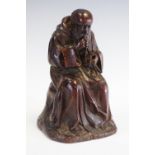 A 19th century oak carving, of a tonsured monk, seated with his rosary, 19.