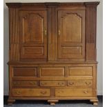 An early 19th century oak country house housekeepers cupboard, outswept cornice, dentil frieze,