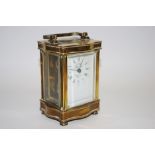 A 20th French brass serpentine carriage clock, with white enamelled dial with Roman numerals,