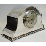 A George V silver plated mantel clock, plannished front, silver dial, black Arabic numerals,