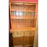 A 20th century pine dresser, oversailing cornice above two adjustable shelves,