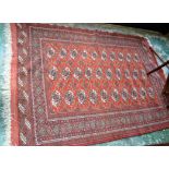 A Middle Eastern rectangular rug, woven in red and blue tones with geometric motifs,