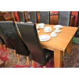 A contemporary light oak dining table, slightly rounded rectangular top, substantial square legs,