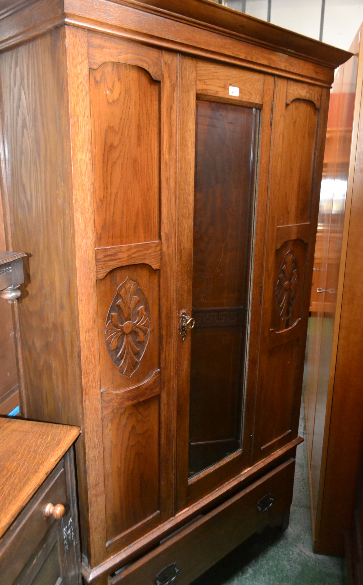 A 20th century oak wardrobe, outswept cornice, central mirrored door, deep drawer to base,