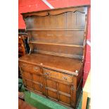 A 20th century oak dresser, outswept cornice above a shaped apron and two plate racks,