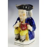 A 19th century Toby jug, seated holding a jug of beer, wearing a tricorn hat, cobalt blue jacket,