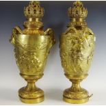 A pair of gilt metal trophy shaped table lamps, embossed with cherubs and swags,