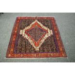 A hand woven Bijar rug, geometric designs in hues of cobalt, cream and taupe on a red ground.