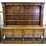 A George III style farmhouse dresser, outswept cornice and shaped apron above three shelves,