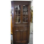 A mid-20th century Royal Oak-style splay-fronted floorstanding corner cabinet.