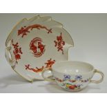 A Meissen leaf shaped dish, painted with a red dragons, gilt line rim, rustic loop handle,