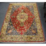 A Bangladeshi rug floral patterns in hues of cream and taupe on a red and blue ground.