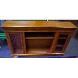 A reproduction yew veneered low bookcase, adjustable shelving flanked by glazed cupboards,