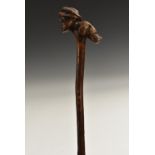 A 19th century folk art walking stick, the handle carved as a huntsman and his hound,