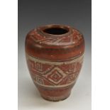 A South American terracotta ovoid vase, banded in white with a geometrical pattern,