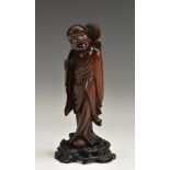 A Chinese hardwood figure, carved as a monk holding a blossoming branch, 18.5cm high, c.