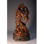 A Chinese hardwood carving, of a monk beneath a pine tree, 16.