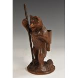 A Black Forest carving, of a bear, he stands, holding a staff, a wicker hod on his back,