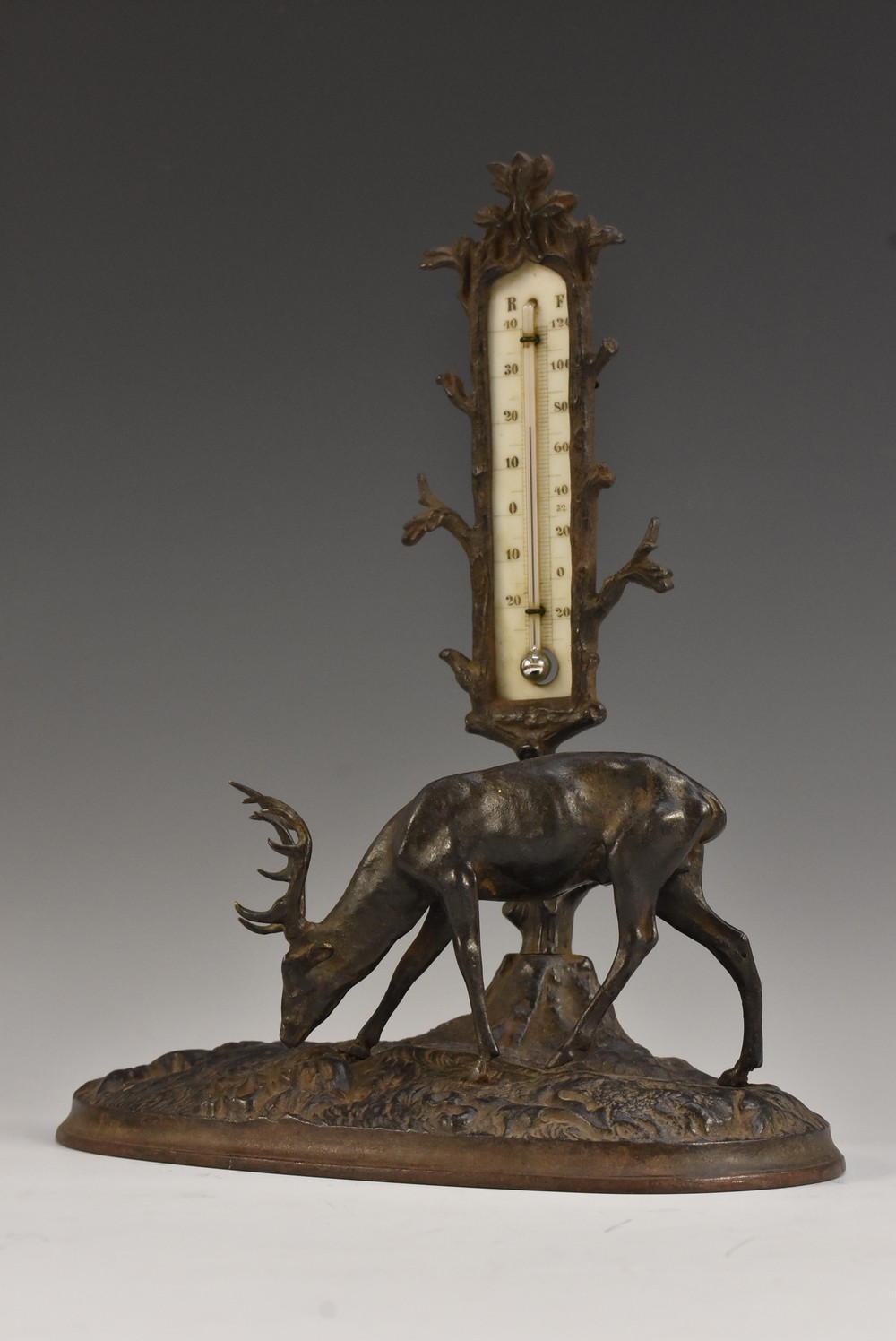 A 19th century cast iron table thermometer, as a stag grazing beside a tree, oval base, 22cm wide,