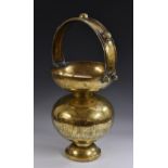 A large Indian brass alms bowl, arched handle, engraved with a tiger hunt, circular base, 56cm high,