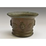 A late 17th century bronze mortar, flared rim, the side applied with masks and shells, 9cm high, c.