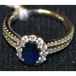 A contemporary sapphire and diamond cluster ring, central oval deep blue sapphire approx 1.