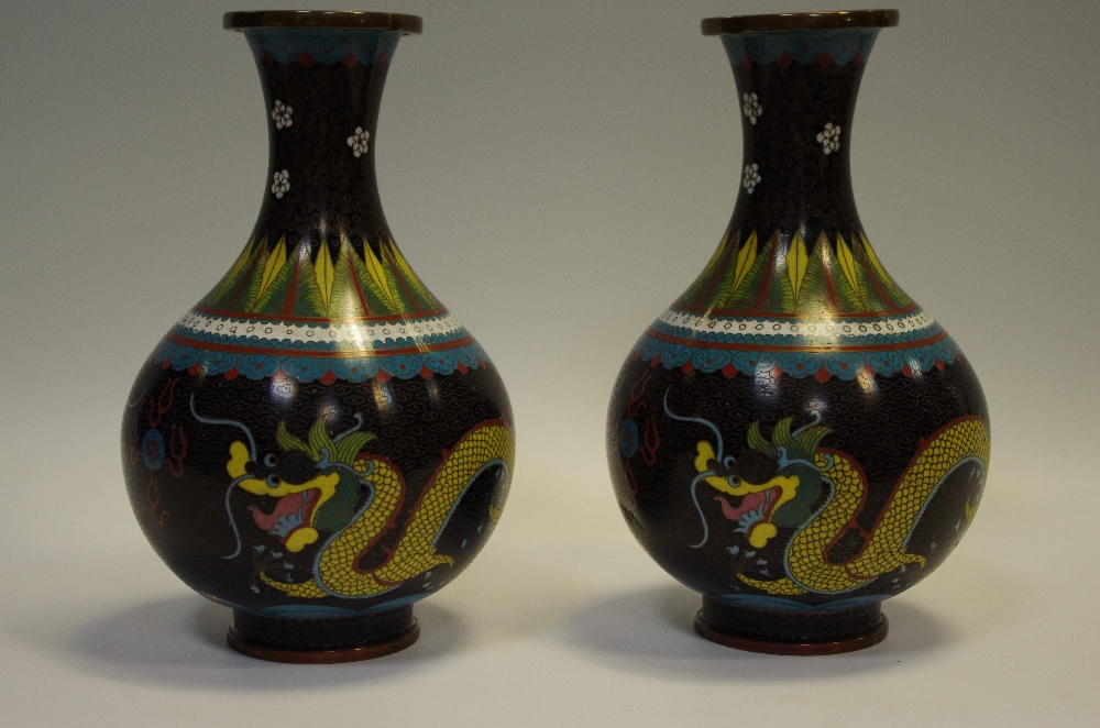 A pair of late 19th century cloisonne enamel vases depicting a ferocious dragon chasing the flaming