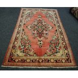 A hand woven Mahal rug, floral designs on a salmon red ground. 207cm x 130cm.