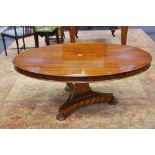 A mahogany oval coffee table, triangular column, incurved trefoil base,