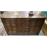 An Ercol dark oak sideboard, oversailing top, four drawers flanked by cupboards, stile feet.