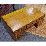 A low elm pedestal desk with an arrangement of seven drawers