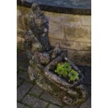 A reconstituted stone garden gnome pushing a wheelbarrow,