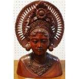 An Indonesian hardwood carving of a deity in traditional headdress.